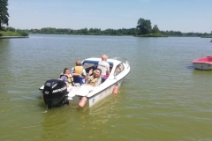 Uczestnicy ŚDS płyną łódką ratowniczą po zalewie Janowskim z ratownikiem WOPR nr 10.