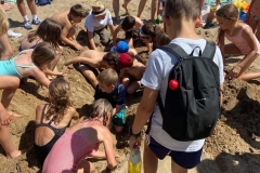 Uczestnicy ŚDS i dzieci z kolonii kopią w piasku na plaży nad Zalewem Janowskim.