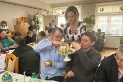 Uczestnicy podczas Spotkania Wielkanocnego, Dyrektor ŚDS częstuje babką