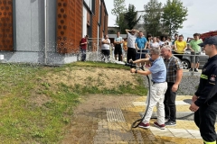 Uczestnik ŚDS leje wodę z węża strażackiego 