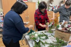 Uczestniczki  ŚDS pod okiem terapeuty samodzielnie wykonują stroik Bożonarodzeniowy