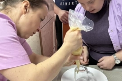 Uczestnicy ŚDS podczas warsztatów cukierniczych robią tort