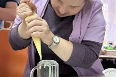 Uczestnicy ŚDS podczas warsztatów cukierniczych uczą się metody strojenia tortów