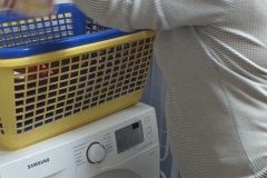 Uczestnik wkłada brudne pranie do pralki