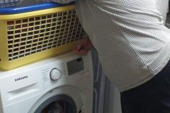 Uczestniczka wkłada brudne pranie do pralki