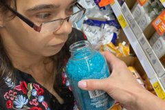 Uczestniczka ŚDS w supermarkecie wącha świeczkę zapachową. Biorą udział w treningu zakupowym i budżetowym
