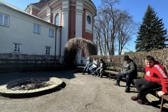 Uczestnicy ŚDS na placu maryjnym przy kościele siedzą na ławce