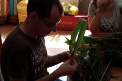 Uczestnicy podczas warsztatów florystycznych wykonują prace z żywymi trawami