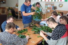 Uczestnicy podczas warsztatów florystycznych wykonują  prace z mchu, wrzosu i roślin