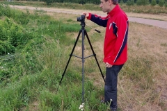 Uczestnik ŚDS robi zdjęcie aparatem fotograficznym, fotografuje krajobraz zalewu Janowskiego.