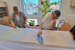 Uczestnicy ŚDS podczas treningu prasują firany 