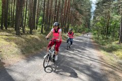 Grupa uczestników ŚDS jadą rowerami po Lasach Janowskich.